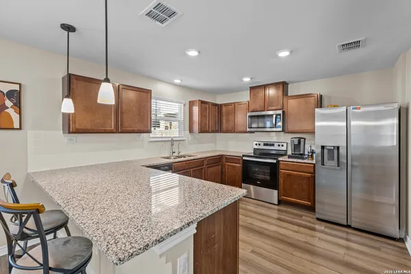 a kitchen with stainless steel appliances granite countertop a sink refrigerator and cabinets
