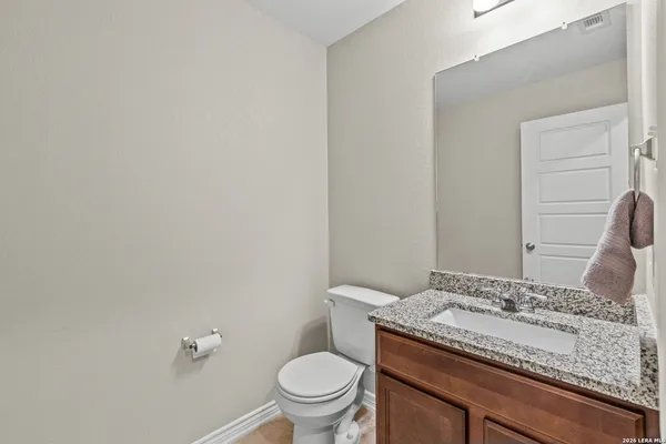 a bathroom with a granite countertop toilet and a sink