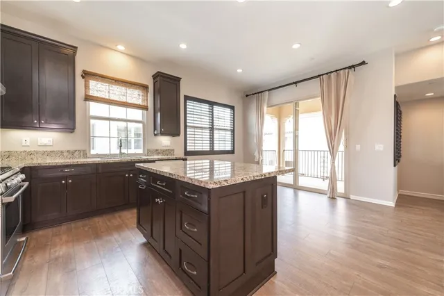 an open kitchen with kitchen island a sink wooden floor and stainless steel appliances