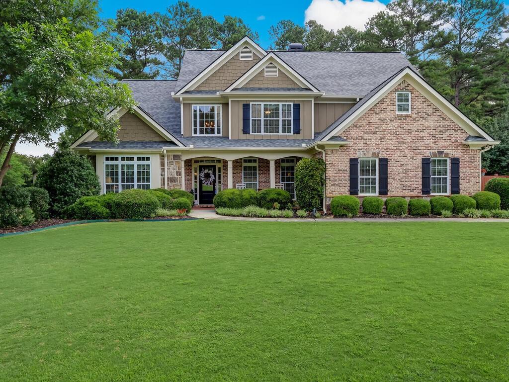 a front view of a house with a garden and trees