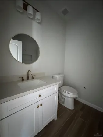 a bathroom with a toilet sink vanity granite and mirror