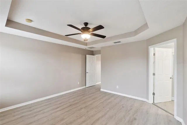 an empty room with wooden floor and a ceiling fan