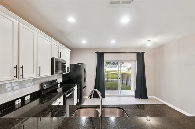 a view of a kitchen with stainless steel appliances granite countertop a sink and a refrigerator
