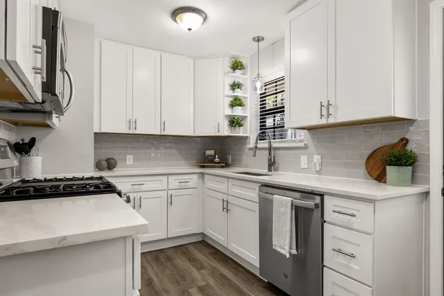 a kitchen with stainless steel appliances white cabinets and a stove a sink