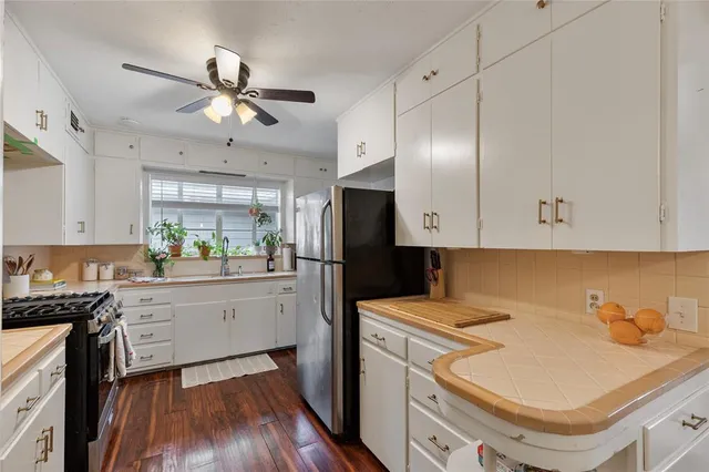 a kitchen with a sink a refrigerator and white cabinets