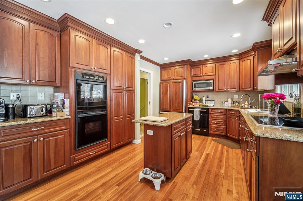406 Indian Road Wayne, NJ 07470 - Photo 15 of 41 a kitchen with stainless steel appliances granite countertop a refrigerator a stove top oven and a sink with wooden floors