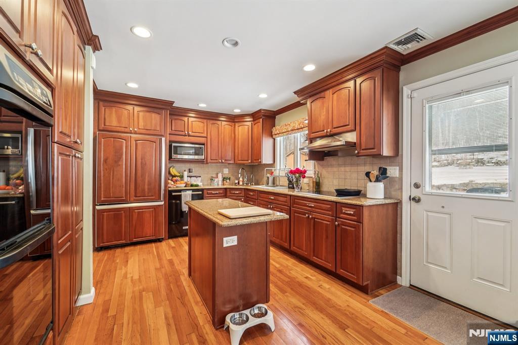 406 Indian Road Wayne, NJ 07470 - Photo 16 of 41 a kitchen with stainless steel appliances granite countertop a refrigerator a sink dishwasher a stove and white countertops with wooden floor