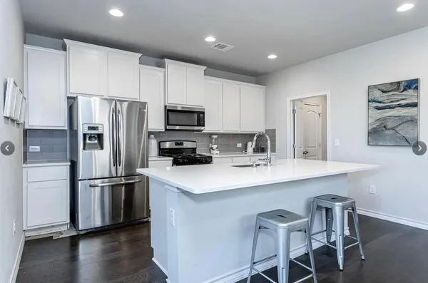 a kitchen with stainless steel appliances a sink stove refrigerator and cabinets