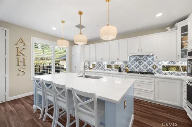 a kitchen with stainless steel appliances kitchen island granite countertop a wooden floor and white cabinets