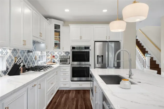 a large white kitchen with a stove a sink dishwasher and a microwave oven with wooden floor