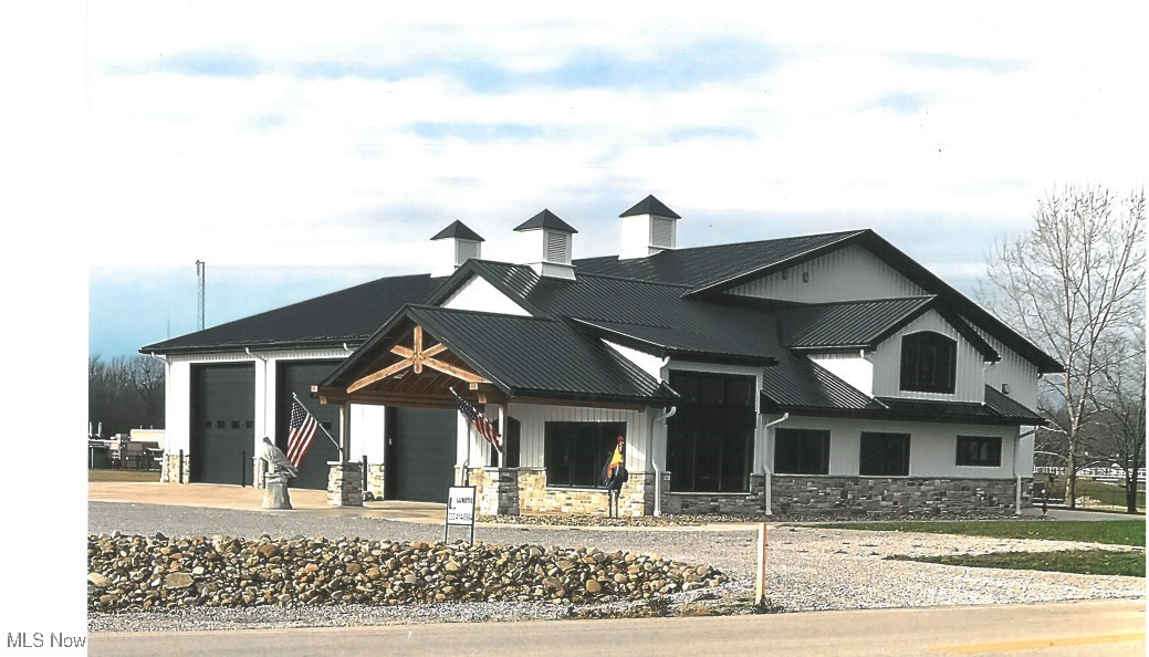 1180 North County Line Road Geneva, OH 44041 - Photo 1 of 33 Modern farmhouse with a garage, stone siding, a metal roof, and concrete driveway