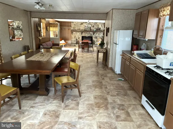 a open kitchen with stainless steel appliances kitchen island granite countertop a table chairs and a refrigerator