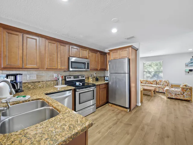 a kitchen with stainless steel appliances granite countertop a refrigerator stove top oven and sink