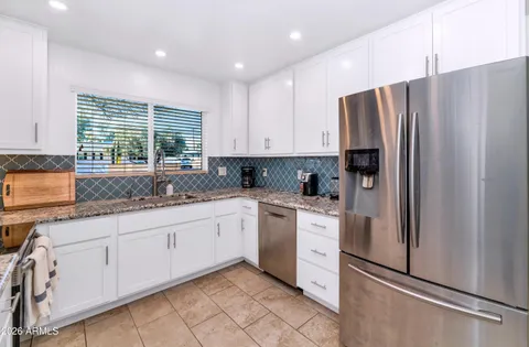 a kitchen with granite countertop white cabinets white stainless steel appliances a sink and a window
