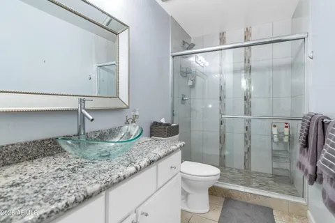 a bathroom with a granite countertop sink a toilet and shower