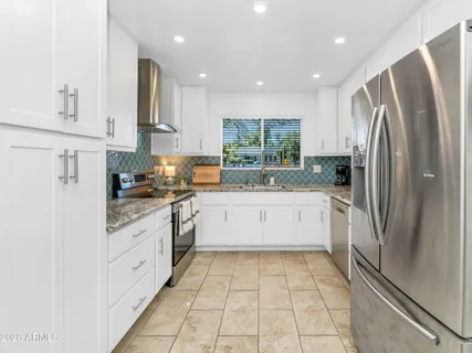 a large kitchen with stainless steel appliances granite countertop a refrigerator and a sink