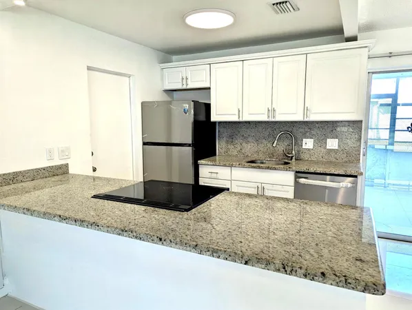 a kitchen with a refrigerator a stove a sink and white cabinets with wooden floor
