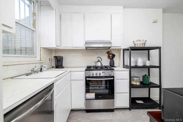 a kitchen with stainless steel appliances a stove and white cabinets