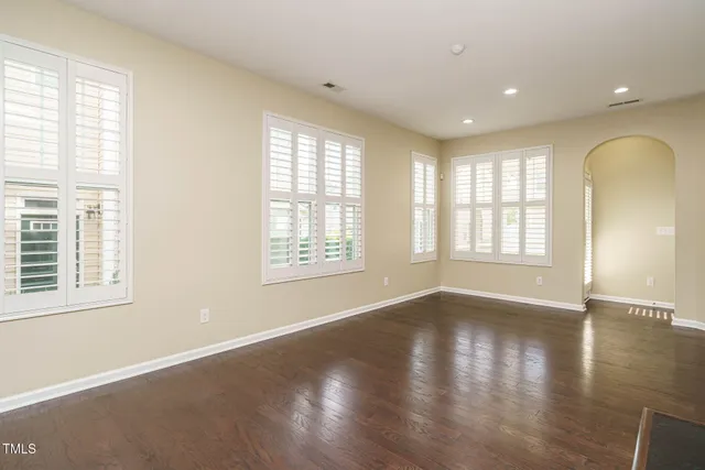 a view of an empty room with wooden floor and a fireplace