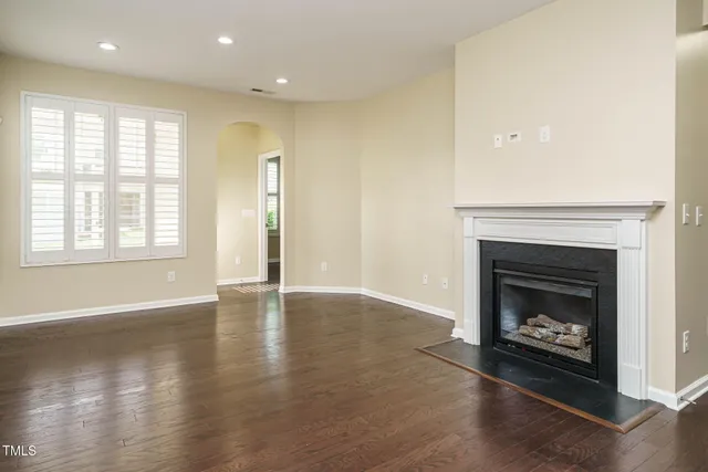 an empty room with windows and fireplace