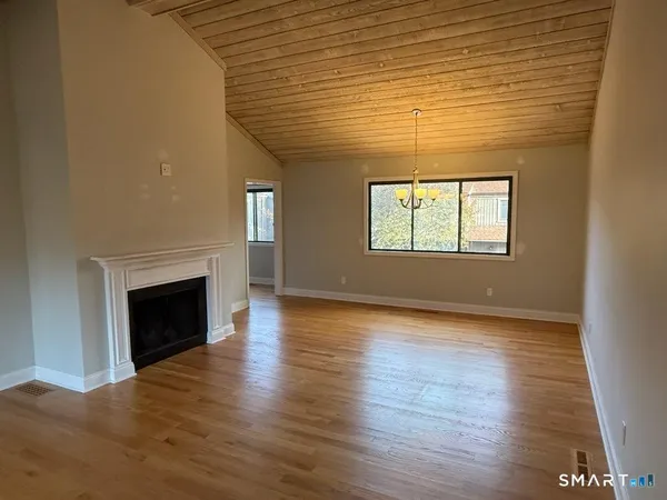 an empty room with wooden floor fireplace and windows