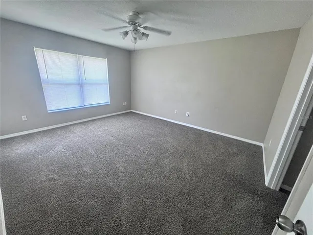 an empty room with windows and fan