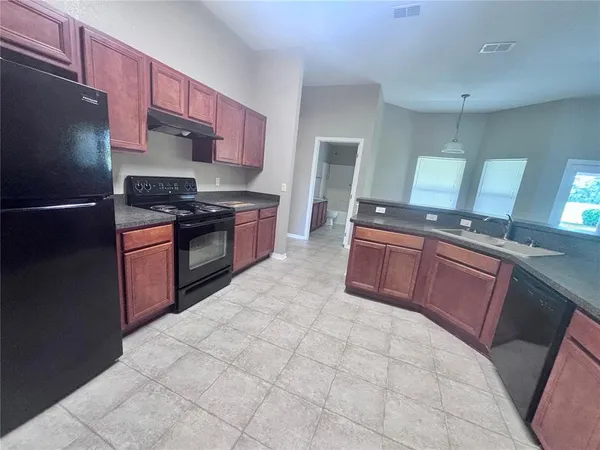 a kitchen with stainless steel appliances granite countertop a stove refrigerator and sink