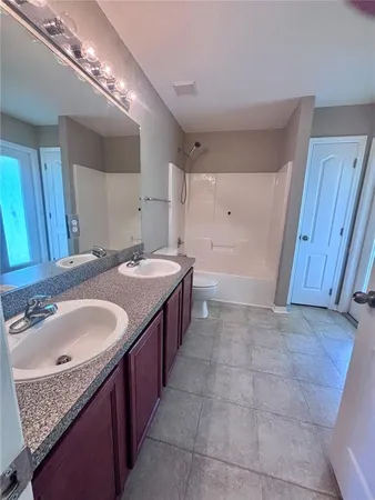a bathroom with a granite countertop double vanity sink and a mirror