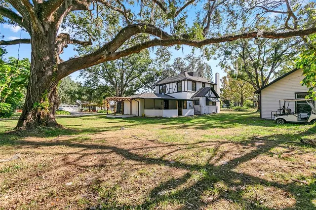a view of a house with a big yard and large trees