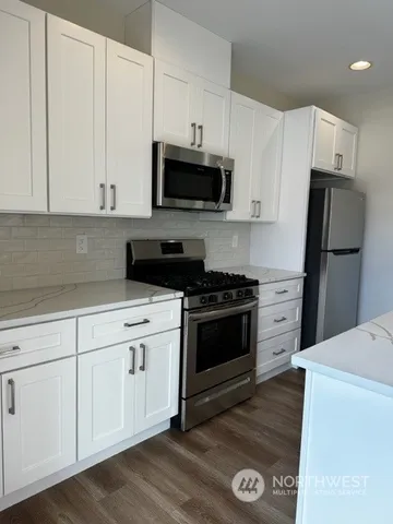 a kitchen with granite countertop a sink dishwasher a stove and a refrigerator with wooden floor