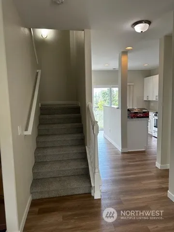 a view of a hallway view with wooden floor and a living room