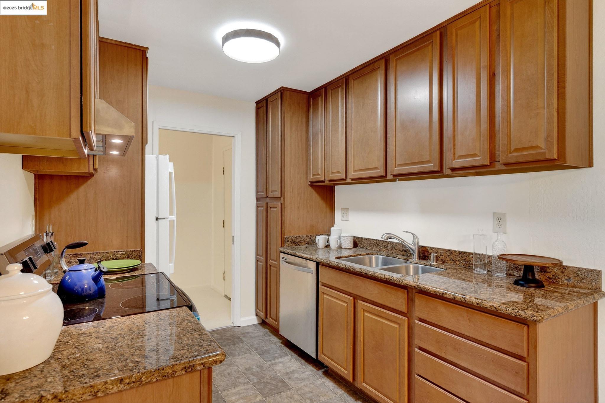 1311 Webster Street, Unit E316 Alameda, CA 94501 - Photo 15 of 39 a kitchen with stainless steel appliances granite countertop wooden cabinets a sink and dishwasher