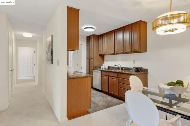 a kitchen with stainless steel appliances granite countertop wooden cabinets a stove a sink a dining table and chairs