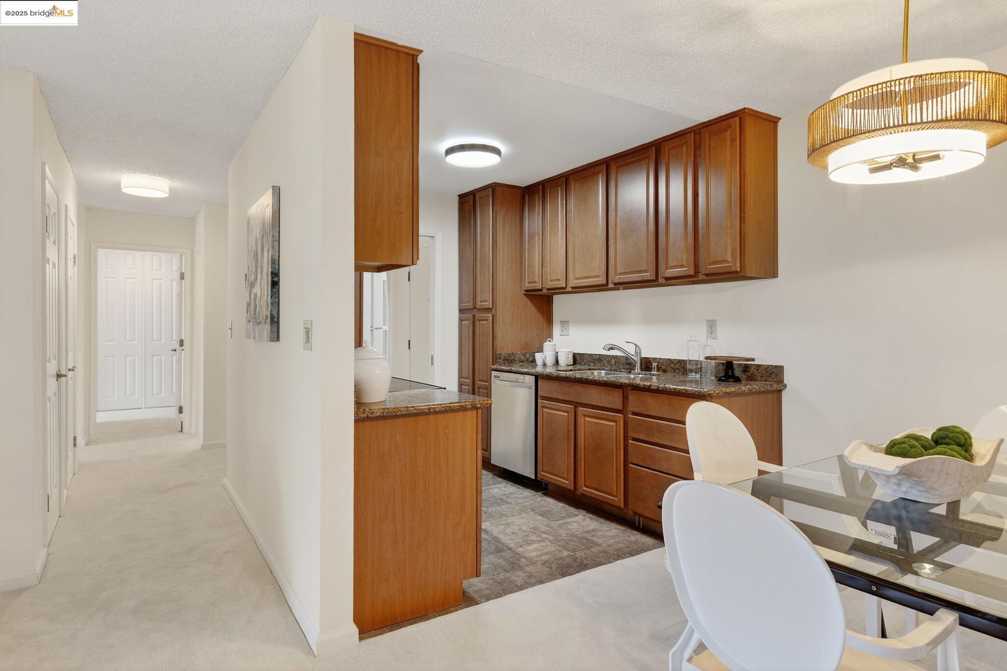 1311 Webster Street, Unit E316 Alameda, CA 94501 - Photo 17 of 39 a kitchen with stainless steel appliances granite countertop wooden cabinets a stove a sink a dining table and chairs