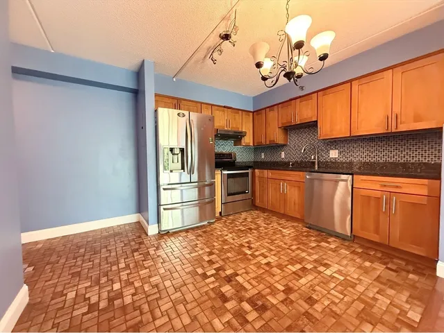 a kitchen with stainless steel appliances granite countertop a stove a sink and a refrigerator