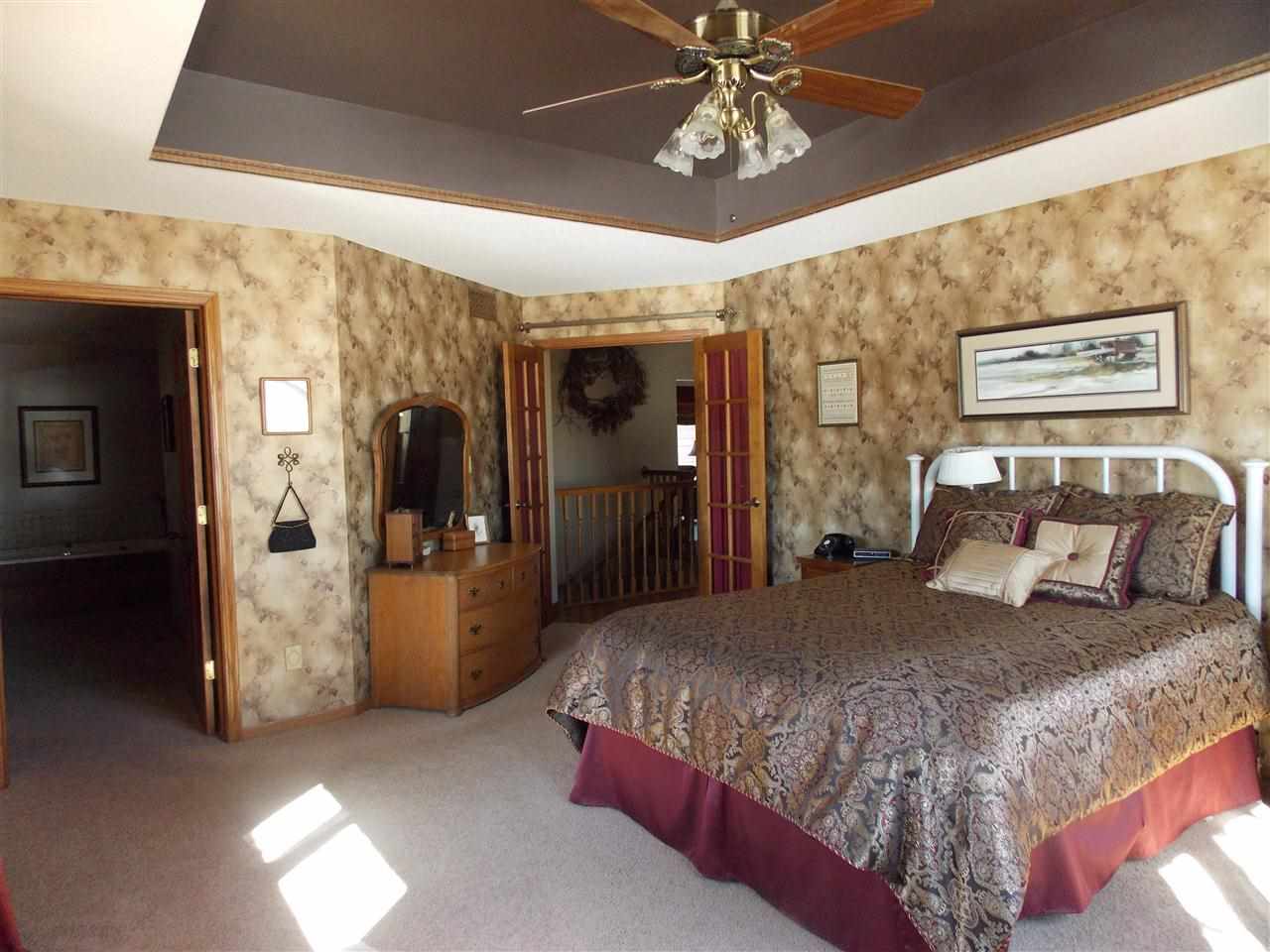 15228 East McNeal Road Monroe Center, IL 61052 - Photo 2 of 25 a bedroom with a large bed and a chandelier