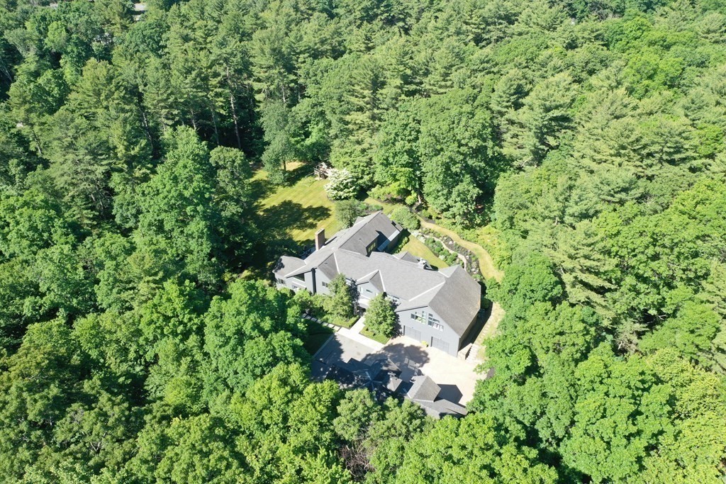 an aerial view of residential house with outdoor space and trees all around