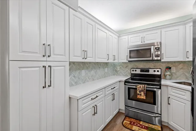 a kitchen with stainless steel appliances granite countertop white cabinets a sink a stove and dishwasher