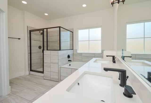 a bathroom with a double vanity sink mirror and a bathtub