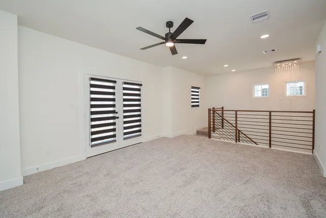 an empty room with ceiling fan and windows