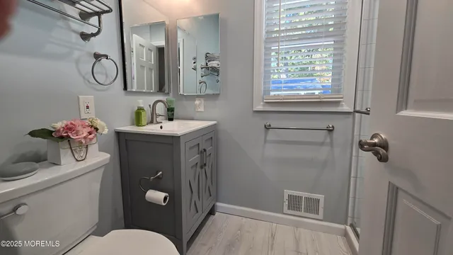a bathroom with a toilet sink vanity granite and mirror