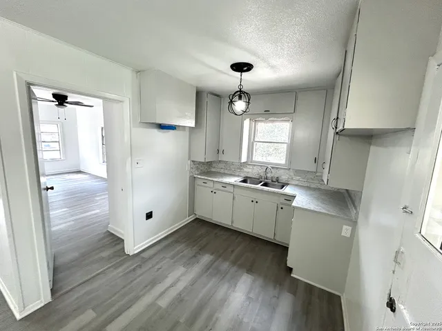 a kitchen with a refrigerator a sink and wooden floor