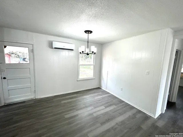 an empty room with wooden floor chandelier and windows