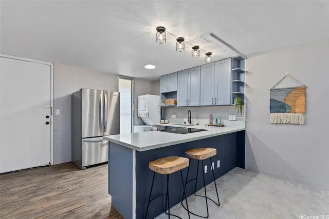 a kitchen with stainless steel appliances granite countertop a refrigerator a sink dishwasher a dining table and chairs with wooden floor