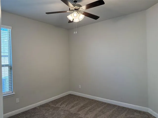 an empty room with a window and chandelier fan