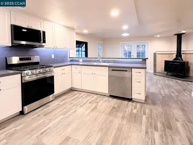 a kitchen with granite countertop a sink cabinets and stainless steel appliances