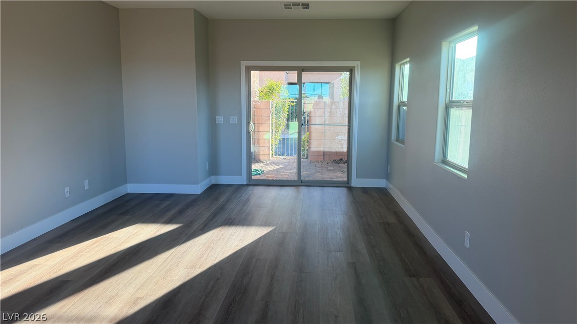 9453 Alma Ridge Avenue Las Vegas, NV 89178 - Photo 2 of 25 Natural light washes over rich hardwood-style flooring, extending to a glass slider that opens to an outdoor space.