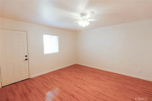 an empty room with wooden floor and chandelier fan