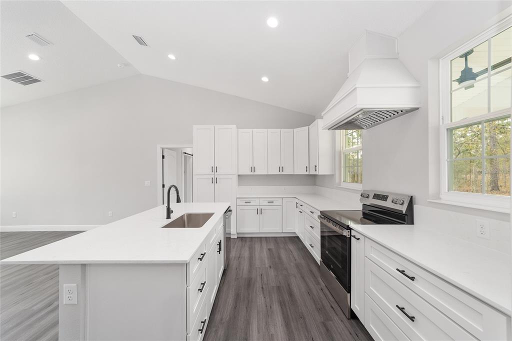 1370 Northeast 151 Avenue Williston, FL 32696 - Photo 18 of 51 a kitchen with a sink dishwasher a stove and white cabinets with wooden floor