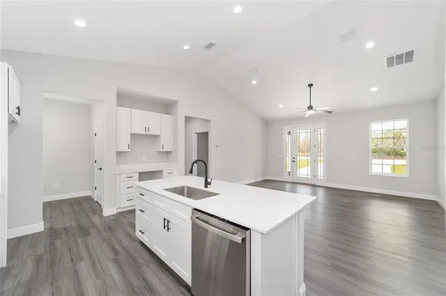 a view of a kitchen with kitchen island a sink dishwasher a stove and a refrigerator with wooden floor